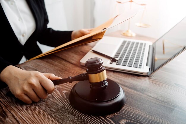 Concept de justice et de droitJuge masculin dans une salle d'audience avec le marteau travaillant avec un ordinateur et des lunettes de clavier d'amarrage sur la table à la lumière du matin