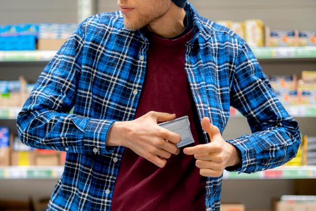 Le concept de kleptomanie un homme dans l'épicerie qui vole de la nourriture et la met dans la poche