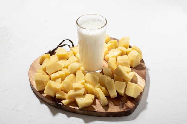 Concept de lait de pomme de terre Lait alternatif Un verre de lait sur une planche de bois avec des pommes de terre crues hachées