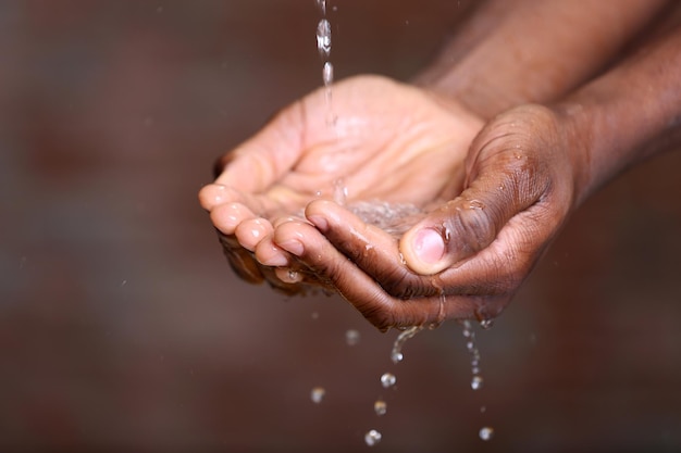 Concept de lavage des mains Verser de l'eau dans les mains de l'homme sur fond de mur de briques