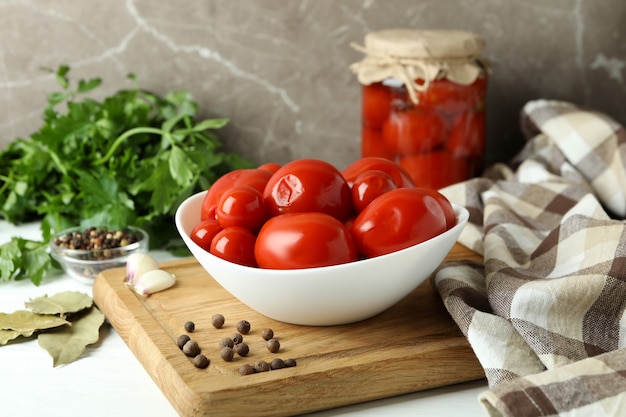 Concept de légumes marinés avec des tomates sur une table en bois blanche