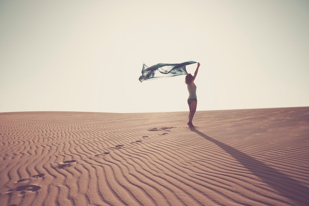 Concept de liberté et de bonheur avec dame debout dans le désert de sable des dunes profitant de la nature oudoor avec un ciel blanc clair