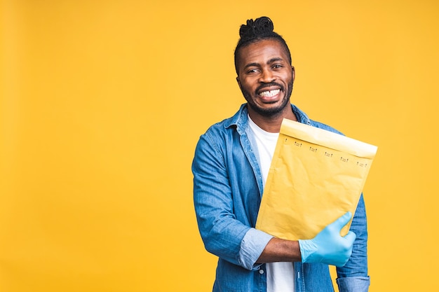 Concept de livraison. Livraison afro-américaine homme noir transportant un colis isolé sur fond jaune.