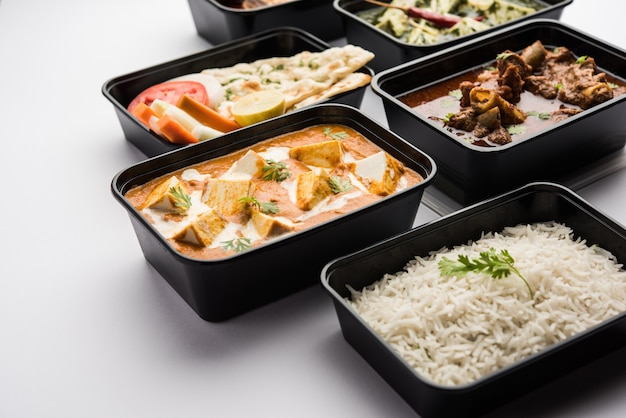 Concept de livraison de nourriture en ligne Beurre de paneer indien masala et palak paneer, curry de mouton et de poulet avec roti et riz dans des récipients en plastique, aliments comme le poulet au beurre, le poulet