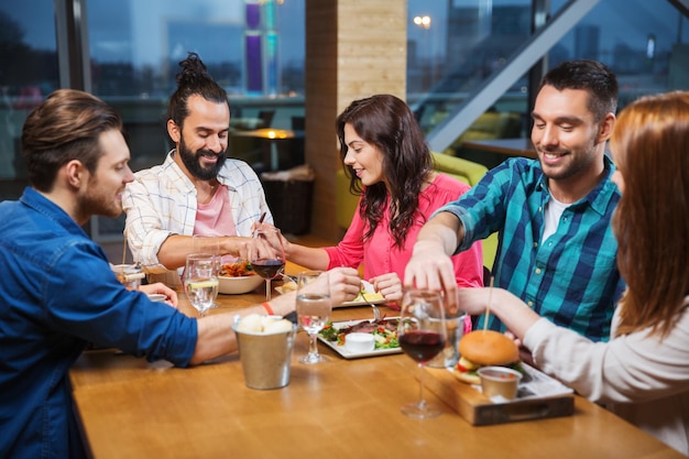 concept loisirs, alimentation, nourriture, personnes et vacances - amis souriants en train de dîner et de goûter les uns les autres au restaurant