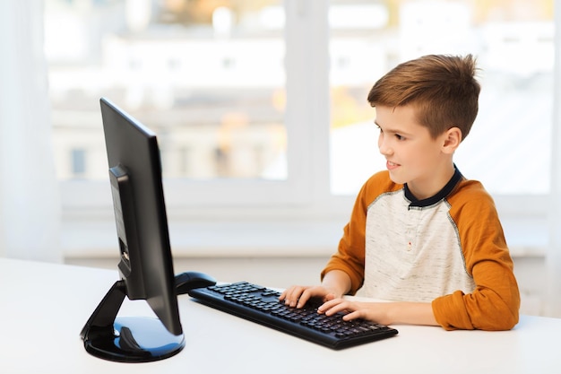 concept de loisirs, d'enfants, d'éducation, de technologie et de personnes - garçon souriant avec ordinateur à la maison