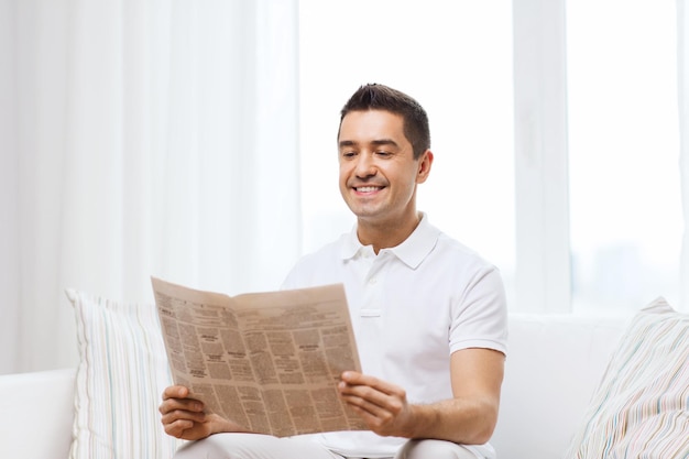 concept de loisirs, d'information, de personnes et de médias de masse - homme heureux lisant le journal à la maison