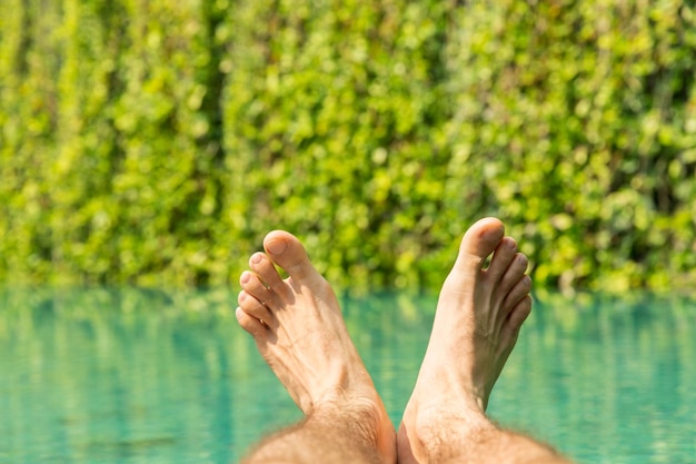 concept de loisirs, de personnes, de voyages et de tourisme - gros plan de pieds masculins sur la piscine du complexe