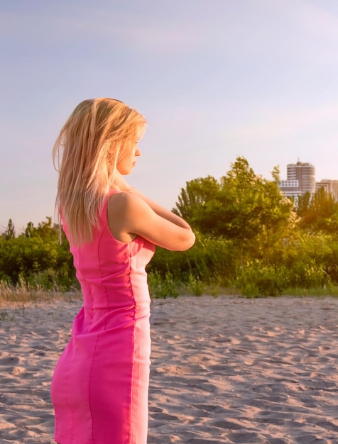 Concept de loisirs de plein air. Fille seule sur la plage dans une robe rose