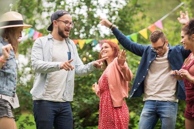 concept loisirs, vacances, amusement et personnes - amis heureux dansant à la fête d'été dans le jardin