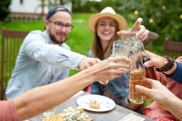 Concept de loisirs, de vacances, de gastronomie, de repas et de nourriture - heureux amis en train de dîner à la fête dans les jardins en été