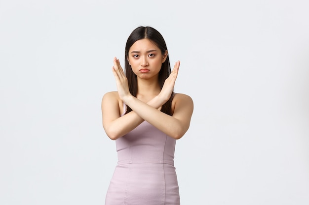 Concept de luxe femmes, fête et vacances. Femme asiatique sérieuse en robe de soirée faisant un geste croisé, dites d'arrêter