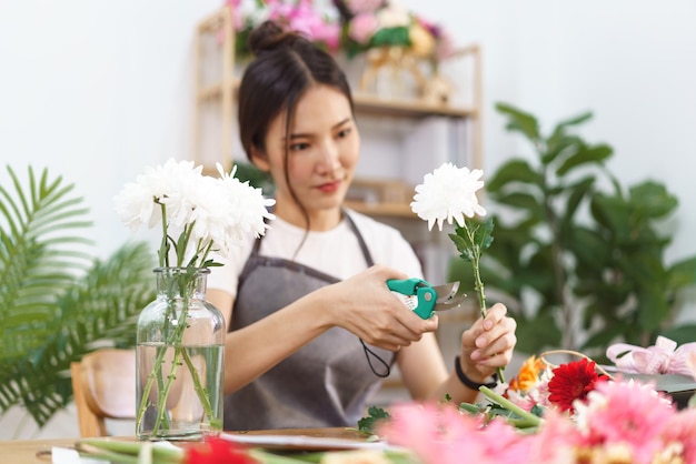 Concept de magasin de fleurs Femme fleuriste garniture feuille de chrysanthèmes avec des ciseaux pour l'arrangement dans un vase