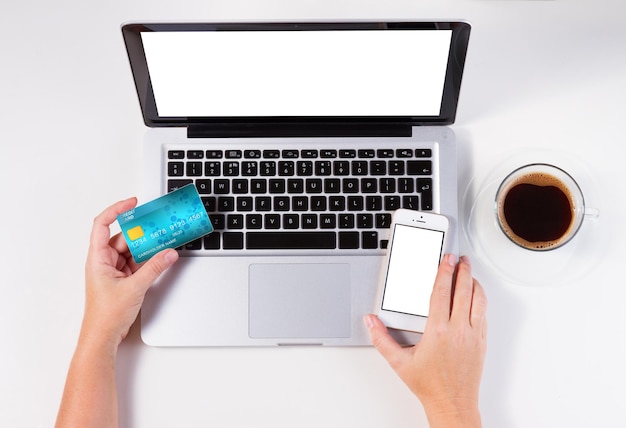 Concept de magasinage en ligne bureau avec ordinateur portable et mains tenant carte de crédit et téléphone