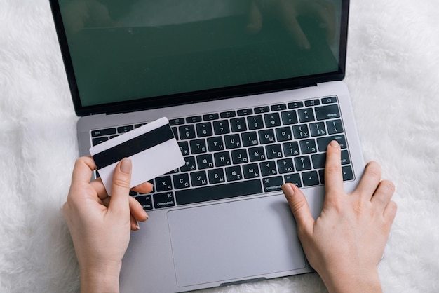 Concept de magasinage en ligne mains de femme tiennent un ordinateur portable de carte bancaire sur fond