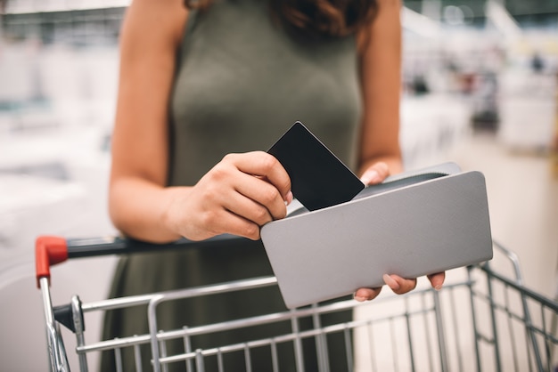 Concept de magasinage et de vente au détail. Femme au supermarché en prenant une carte de crédit de son portefeuille.