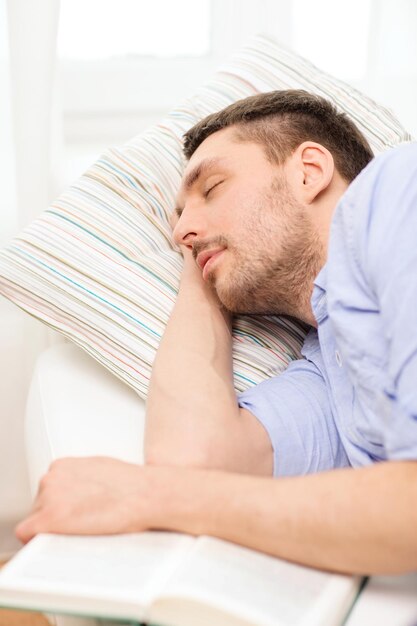 concept de maison et de bonheur - jeune homme calme allongé sur un canapé à la maison avec un livre