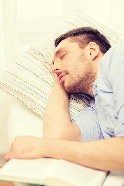 concept de maison et de bonheur - jeune homme calme allongé sur un canapé à la maison avec un livre