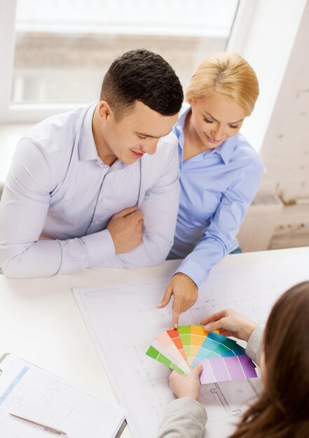 concept de maison, de design et d'architecture - couple souriant regardant des échantillons de plans et de couleurs au bureau