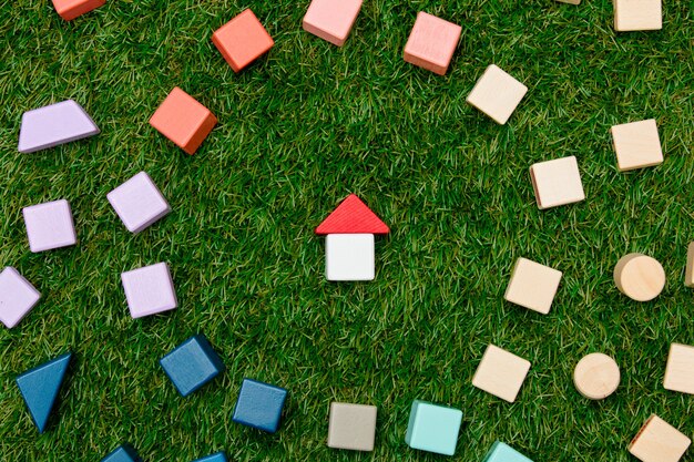 Photo concept de maison de jouet en bois et autres blocs autour de l'herbe verte.