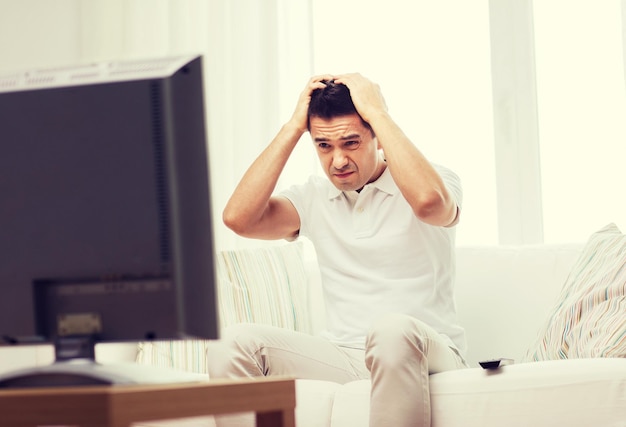 concept de maison, de personnes, de technologie et de divertissement - homme déçu regardant le sport à la télévision et soutenant l'équipe à la maison