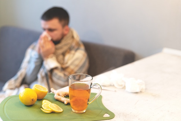 Le concept de la maladie, l'heure d'hiver. Thé noir, citron et gingembre sur la table, un homme malade, grippe. Épidémie, congé de maladie, température, stress