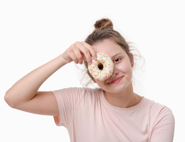 Concept de malbouffe Jeune jolie fille tient un beignet sucré devant ses yeux