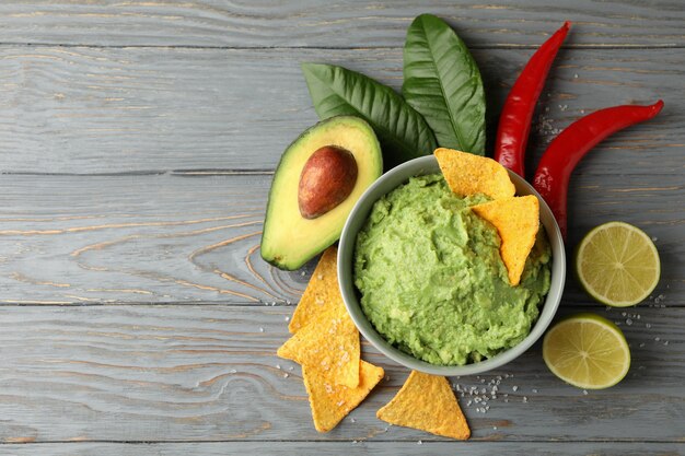 Concept de manger savoureux avec bol de guacamole sur fond de bois, espace pour le texte