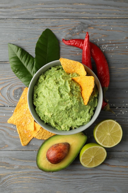 Concept de manger savoureux avec bol de guacamole sur fond de bois, vue du dessus