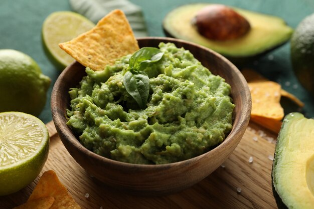 Concept de manger savoureux avec bol de guacamole sur fond texturé vert