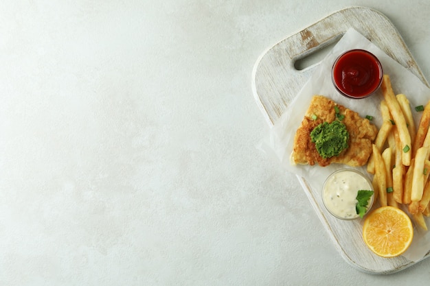 Concept de manger savoureux avec du poisson frit et des frites sur fond texturé blanc