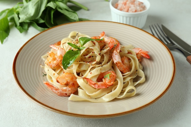 Concept de manger savoureux avec des pâtes aux crevettes sur une table texturée blanche