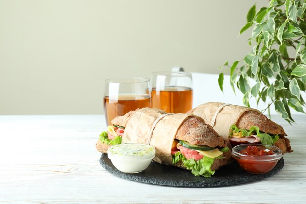 Concept de manger savoureux avec des sandwichs ciabatta sur une table en bois blanc