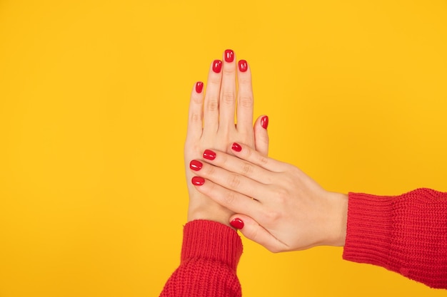 Concept de manucure et de soin des ongles Deux mains de femme avec un vernis à ongles rouge pastel parfait sur fond jaune