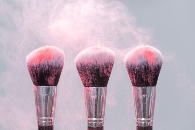 Concept de maquillage, de beauté et de poudre minérale - pinceau avec de la poudre rose sur fond clair.