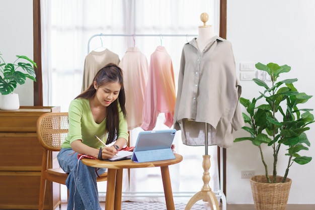 Concept de marchand de vêtements de mode Une blogueuse mesure la taille de la robe et prend des notes sur un ordinateur portable