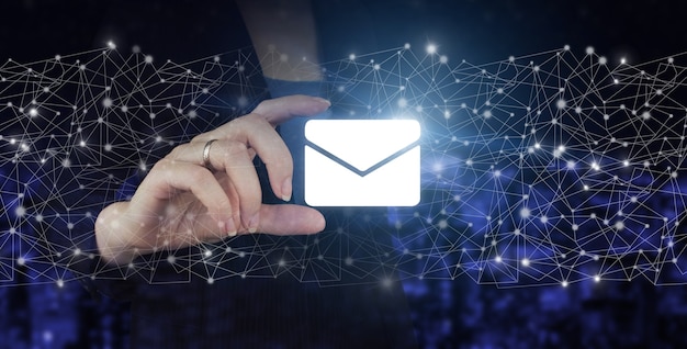 Concept de marketing par e-mail et sms. Tenir à la main l'hologramme numérique Email et sms signe sur fond flou sombre de la ville. Contactez-nous notion.