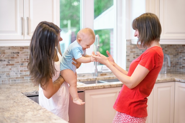 Le concept de maternité, nounou, petite enfance et enfance. Deux femmes et un bébé dans leurs bras.