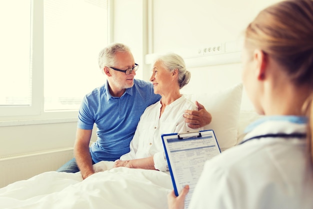 concept de médecine, d'âge, de soins de santé et de personnes - femme âgée, homme et médecin avec presse-papiers à l'hôpital