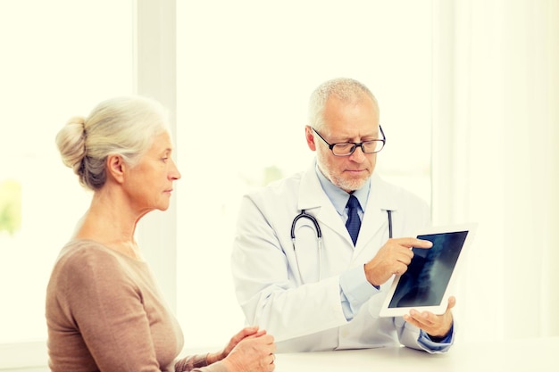 concept de médecine, d'âge, de soins de santé et de personnes - femme âgée et médecin avec réunion d'ordinateur tablette pc dans un cabinet médical