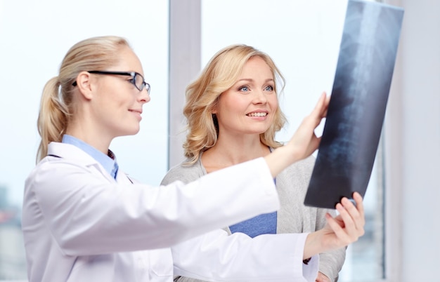 concept de médecine, d'âge, de soins de santé et de personnes - femme heureuse patiente et médecin avec une réunion de radiographie de la colonne vertébrale dans un cabinet médical