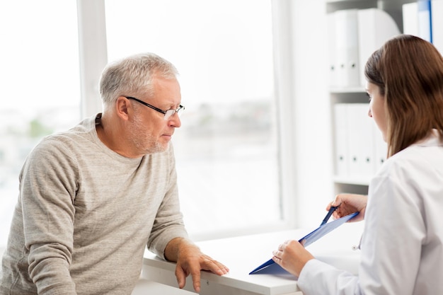 concept de médecine, d'âge, de soins de santé et de personnes - homme senior et médecin avec réunion de presse-papiers dans un cabinet médical à l'hôpital