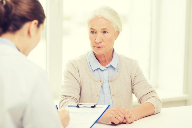 concept de médecine, d'âge, de soins de santé et de personnes - médecin avec presse-papiers écrivant une ordonnance pour une femme âgée à l'hôpital