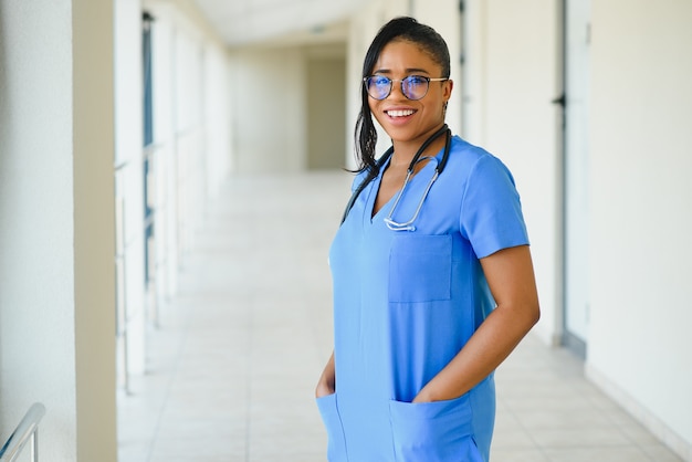 Concept de médecine, de profession et de soins de santé - femme médecin afro-américaine souriante et heureuse avec stéthoscope sur fond d'hôpital