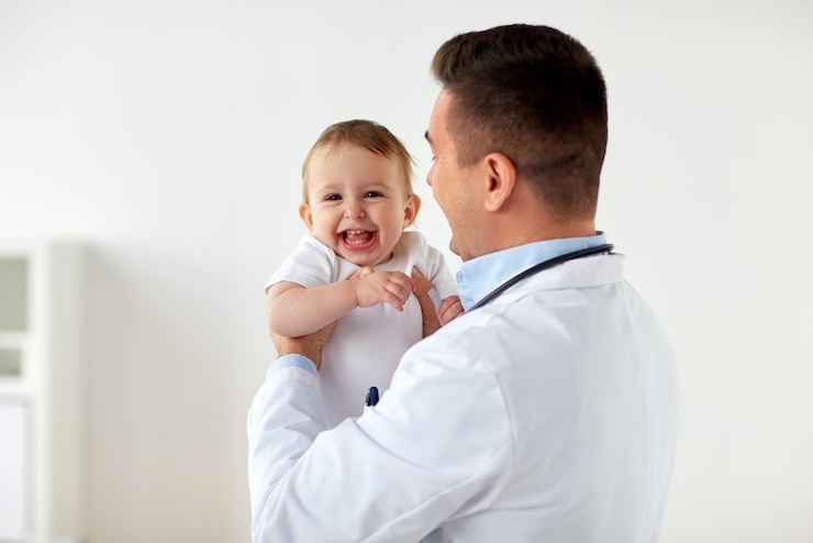 Photo concept de médecine, de soins de santé, de pédiatrie et de personnes - médecin ou pédiatre heureux tenant le bébé lors d'un examen médical à la clinique