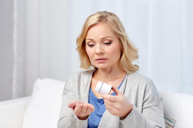 concept de médecine, de soins de santé et de personnes - femme d'âge moyen avec des médicaments à la maison