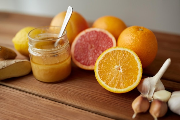 concept de médecine traditionnelle, de cuisine, d'alimentation et d'ethnoscience - miel, agrumes au gingembre et ail sur table en bois