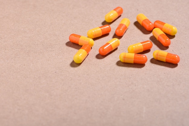Concept médical: pilules blanches et orange et capsules sur fond marron.