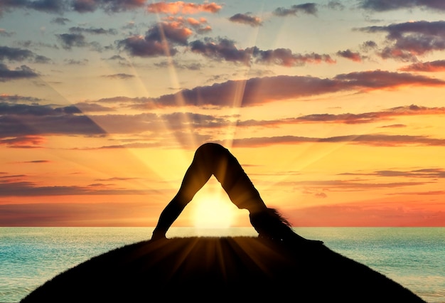 Concept de méditation et de relaxation. Silhouette d'une fille pratiquant le yoga sur fond de coucher de soleil sur la mer