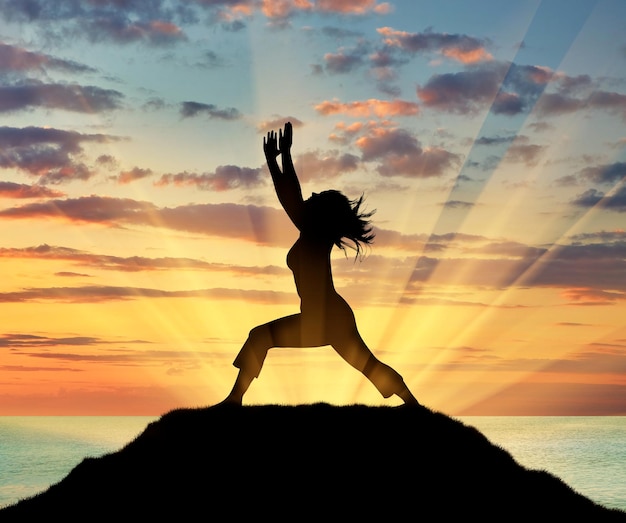 Concept de méditation et de relaxation. Silhouette d'une fille pratiquant le yoga sur fond de coucher de soleil sur la mer